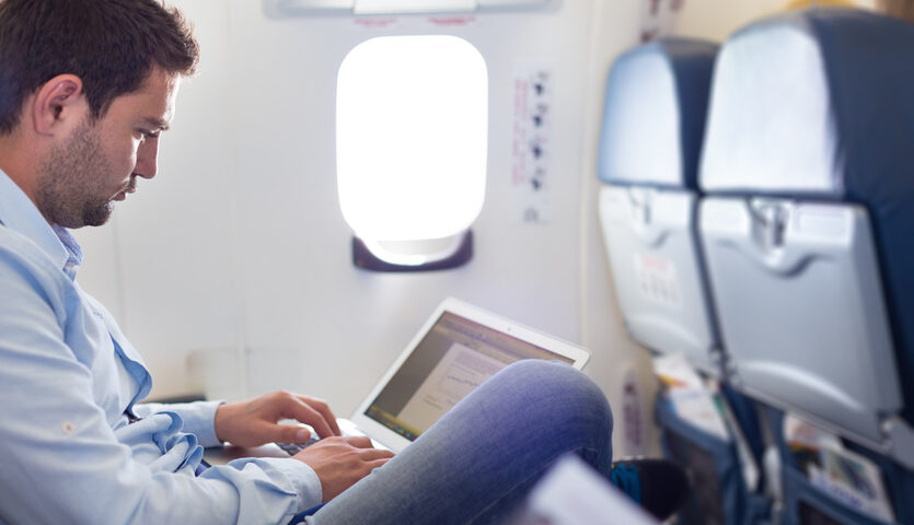 Matej Kastelic / Shutterstock working on laptop in middle seat on airplane