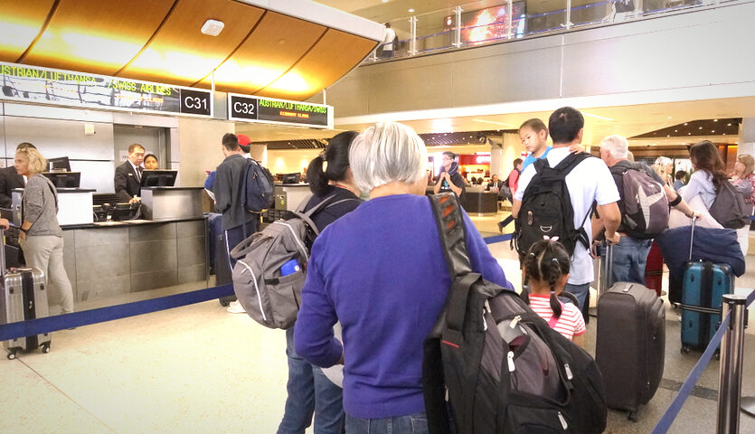 people wait in line at airline check-in ticket counter