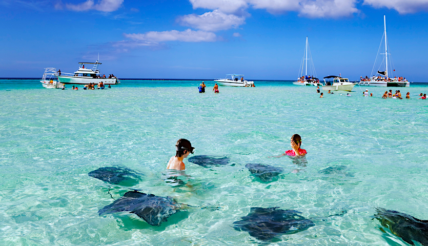 Kids snorkeling with manta rays in Cayman Islands