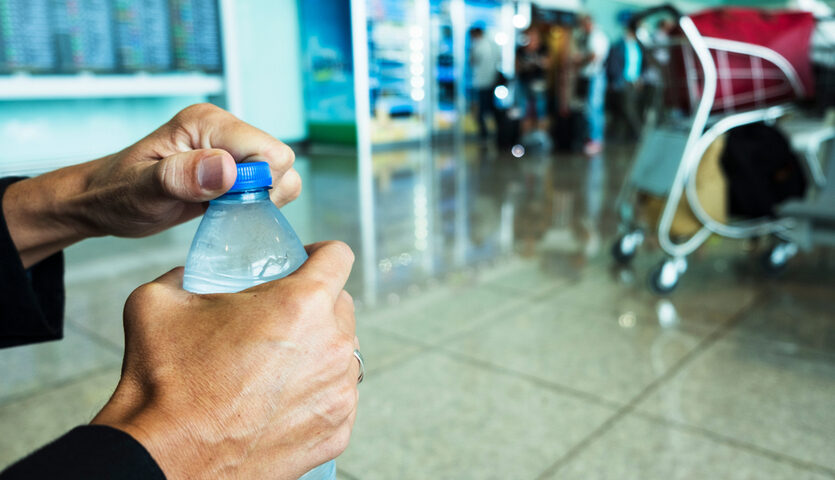hands of man opening water bottle at airport