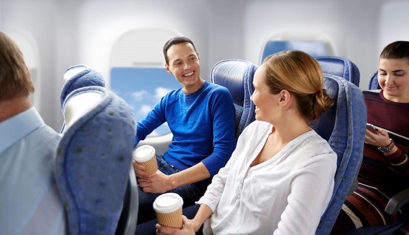 happy-couple-seated-on-plane-with-coffee