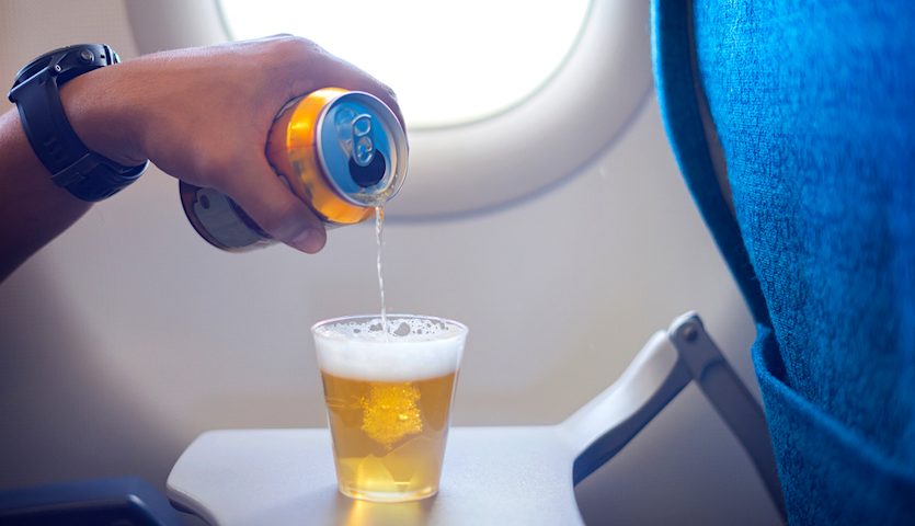 Man pouring a beer into a cup onboard an airplane