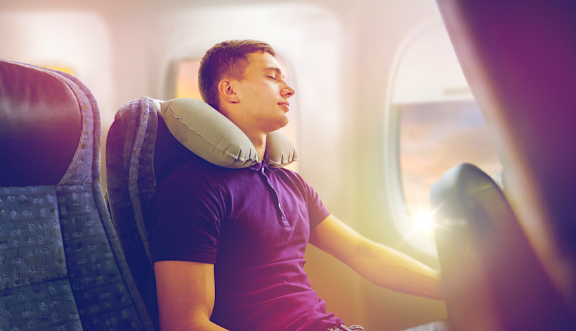 man sleeping on airplane with neck pillow