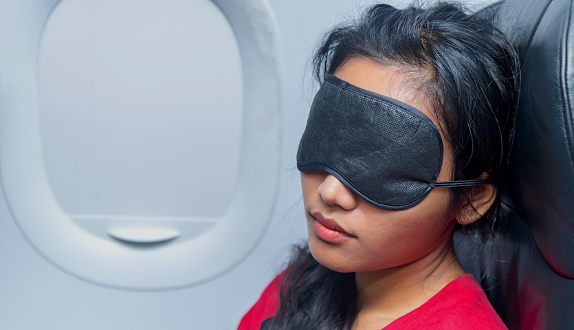 woman sleeping on an airplane with an eyemask