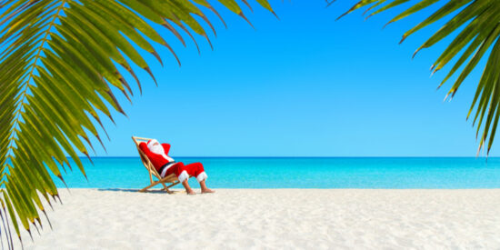 Santa Claus relaxing on a tropical beach celebrating Christmas by the ocean